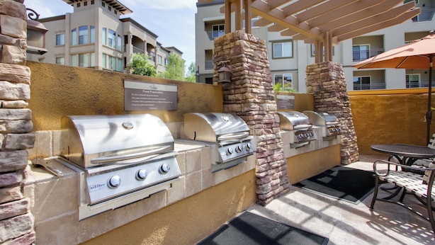 An outdoor barbecue area with multiple grills, a stone pillar, and a pergola. - Mid-century Modern Phoenix Condo, Walk to High St! (Phoenix)
