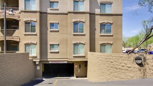 A multi-story building with a garage entrance, a clear sky, and a parked car. - Mid-century Modern Phoenix Condo, Walk to High St! (Phoenix)