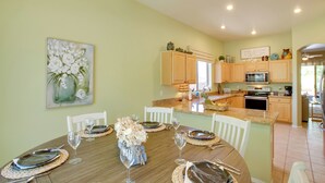 A dining area with a wooden table set for four, surrounded by white chairs. A painting of white flowers hangs on the wall. - Walk to Trails: Mtn-view Mesa Getaway w/ Gril (Mesa)