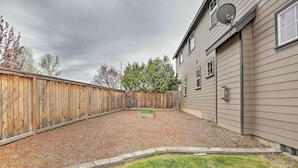 Un jardin avec une clôture en bois, un espace recouvert de gravier et une pelouse.
