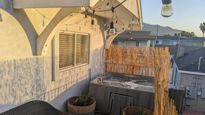 A balcony with a hot tub, wicker furniture, and decorative lighting. - 5 Mi to Universal Studios: Family Gem w/ Hot Tub! (Burbank)