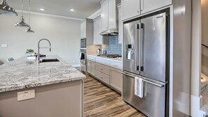 A modern kitchen with a granite countertop, stainless steel appliances, and wooden flooring. - Elegant Lake Conroe Townhome w/ Boat Slip! (Montgomery)