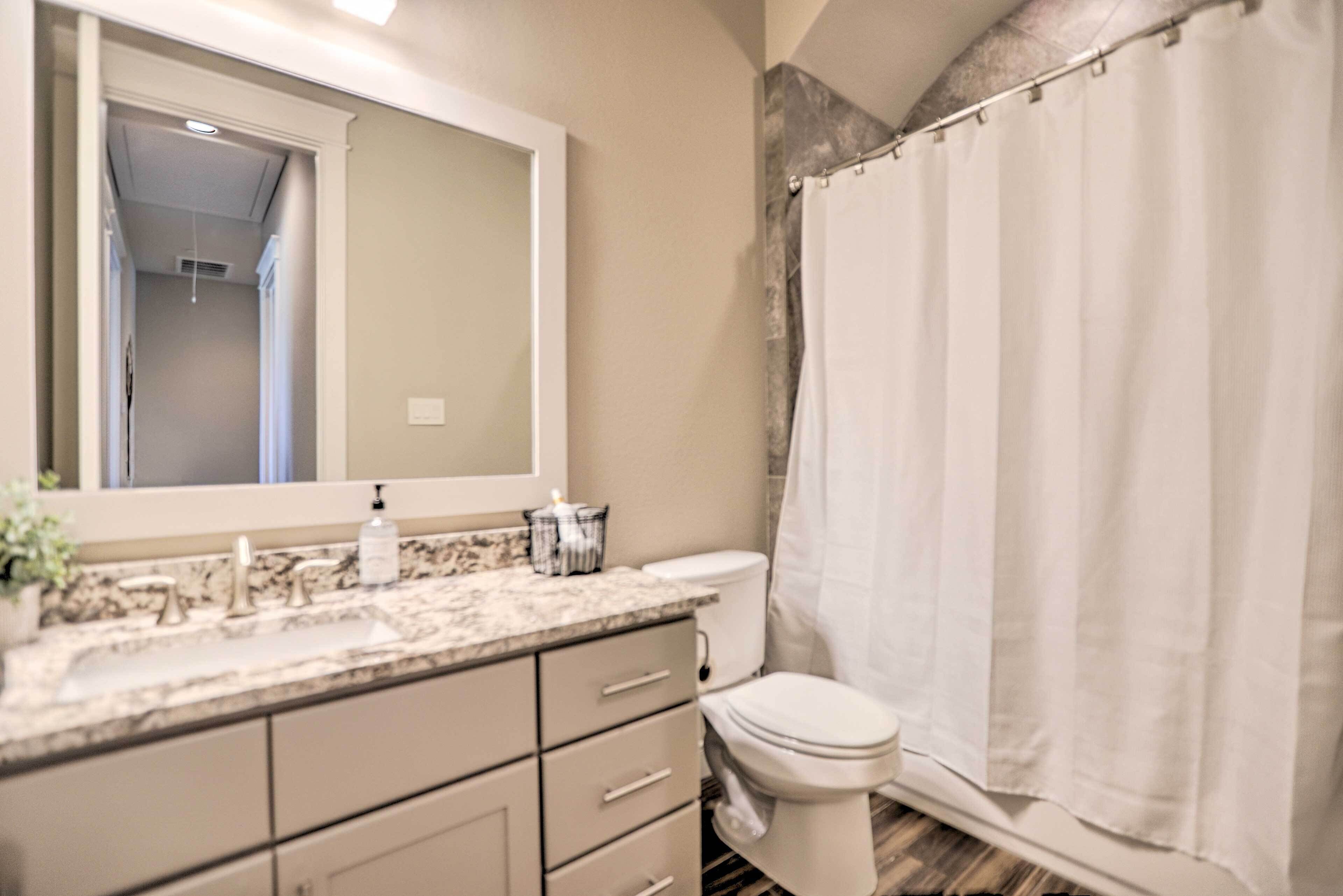 A bathroom with a marble sink, a toilet, and a shower curtain.