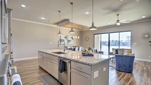 A modern kitchen with a large island, pendant lights, and a view to the living area. - Elegant Lake Conroe Townhome w/ Boat Slip! (Montgomery)