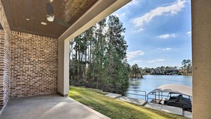 A covered patio with a brick wall, a view of a lake, and a boat dock. - Elegant Lake Conroe Townhome w/ Boat Slip! (Montgomery)