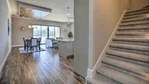 A spacious living area with a dining table, kitchen island, and a staircase leading to an upper floor. - Elegant Lake Conroe Townhome w/ Boat Slip! (Montgomery)