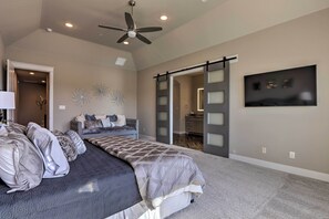 A bedroom with a large bed, a ceiling fan, and a sliding door leading to another room. - Elegant Lake Conroe Townhome w/ Boat Slip! (Montgomery)