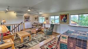 A cozy living room with a wooden floor, a large window, a ceiling fan, and a quilted bedspread. - Columbia Falls Home 19 Mi to Glacier National Park (Columbia Falls)