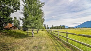 A rural landscape with a wooden fence, a grassy field, and a building with a red roof. - Columbia Falls Home 19 Mi to Glacier National Park (Columbia Falls)