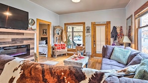 A cozy living room with a fireplace, a television, a sofa, and a dining area. - Lovely Montrose Home w/ Yard: Walk to Dtwn & Park! (Montrose)