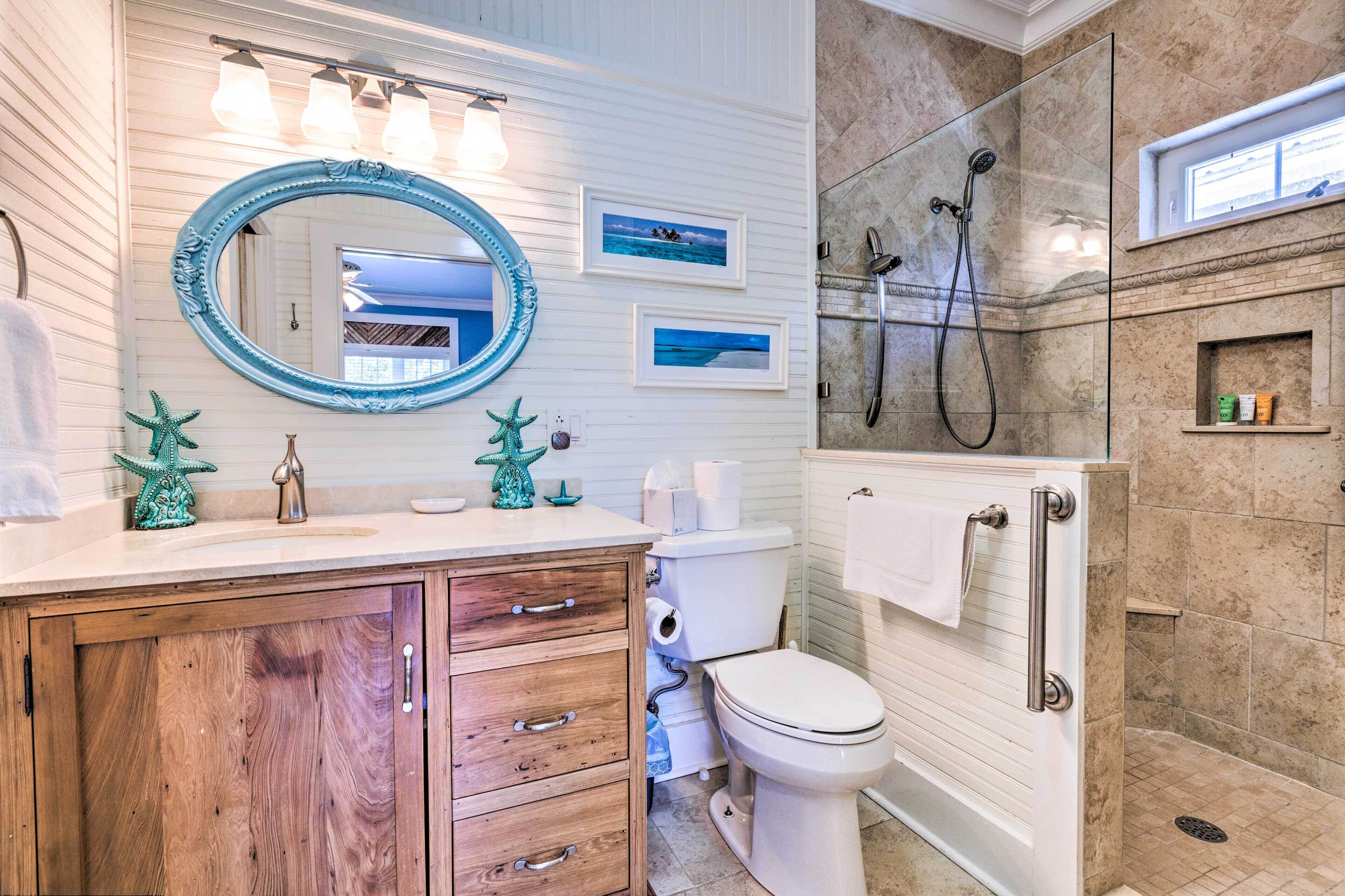 Une salle de bain avec un meuble-lavabo en bois, un grand miroir, une douche et des toilettes.