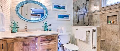 Une salle de bain avec un meuble-lavabo en bois, un grand miroir, une douche et des toilettes.