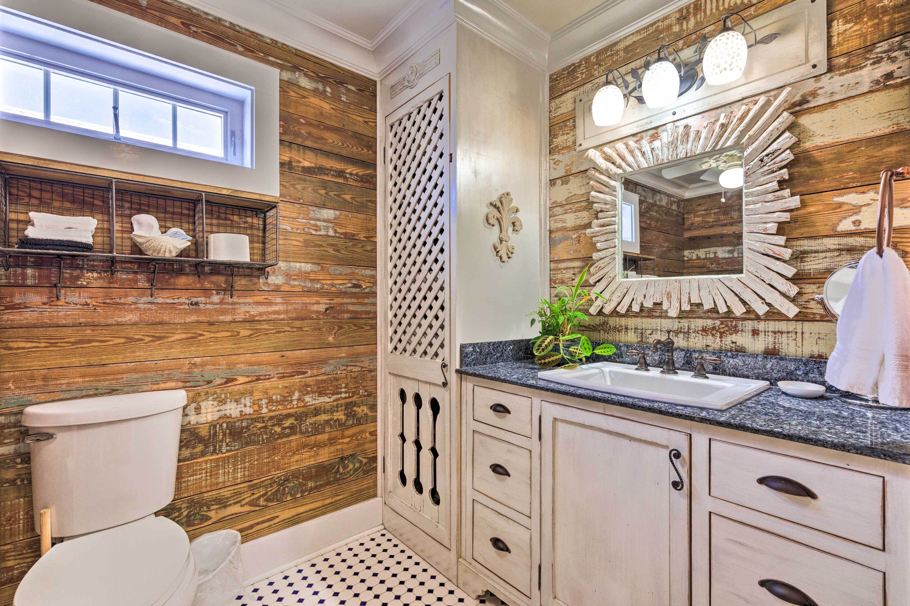 A bathroom with wooden walls, a white toilet, a sink with a mirror, and a shelf with towels.