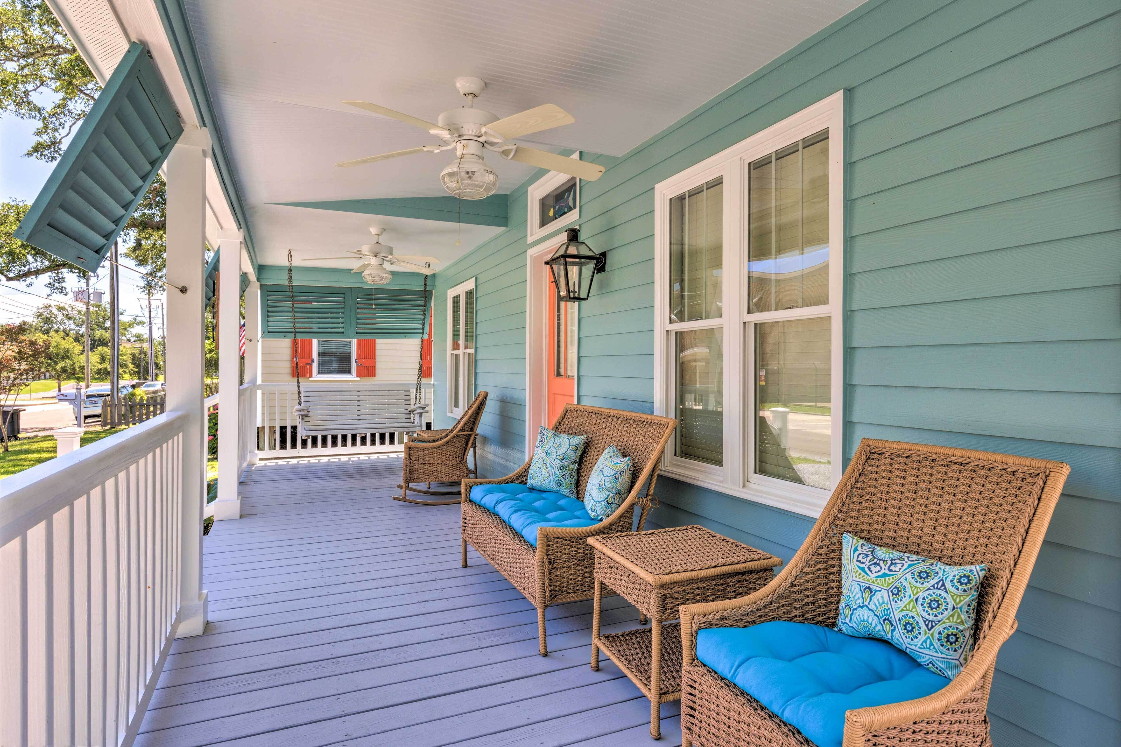 A porch with wicker furniture and a ceiling fan.