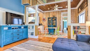 A living room with a blue cabinet, a grey sofa, and a wooden ceiling. - Cottage w/ Porch - 3 Min Walk to Bay St Louis (Bay St Louis)