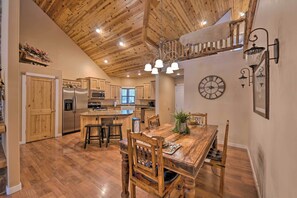 A spacious kitchen with wooden cabinets, a central island, and a dining area with a wooden table and chairs. - Spacious Pinetop Country Club Cabin w/ Deck! (Pinetop)