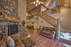 Un vaste espace de vie agrémenté d’une cheminée en pierre, d’un escalier en bois et d’un coin salon confortable.