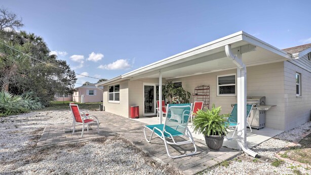 A house with a covered porch, two chairs, a potted plant, and a grill. - Single-story Home: Walk to Beach, Pier & River (Ormond Beach)