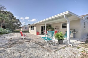 A house with a covered porch, two chairs, a potted plant, and a grill. - Single-story Home: Walk to Beach, Pier & River (Ormond Beach)