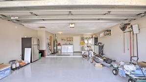 A garage with a kitchen area, a bicycle, and a cart with items. - Single-story Home: Walk to Beach, Pier & River (Ormond Beach)