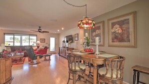 A spacious living room with a dining area, hardwood floors, and a ceiling fan. - Single-story Home: Walk to Beach, Pier & River (Ormond Beach)