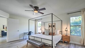 Un dormitorio con cama con dosel, ventilador de techo, mesita de noche con lámpara y un banco.