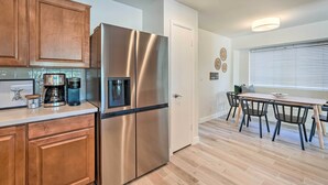 Una cocina moderna con electrodomésticos de acero inoxidable, armarios de madera y un comedor con mesa y sillas.