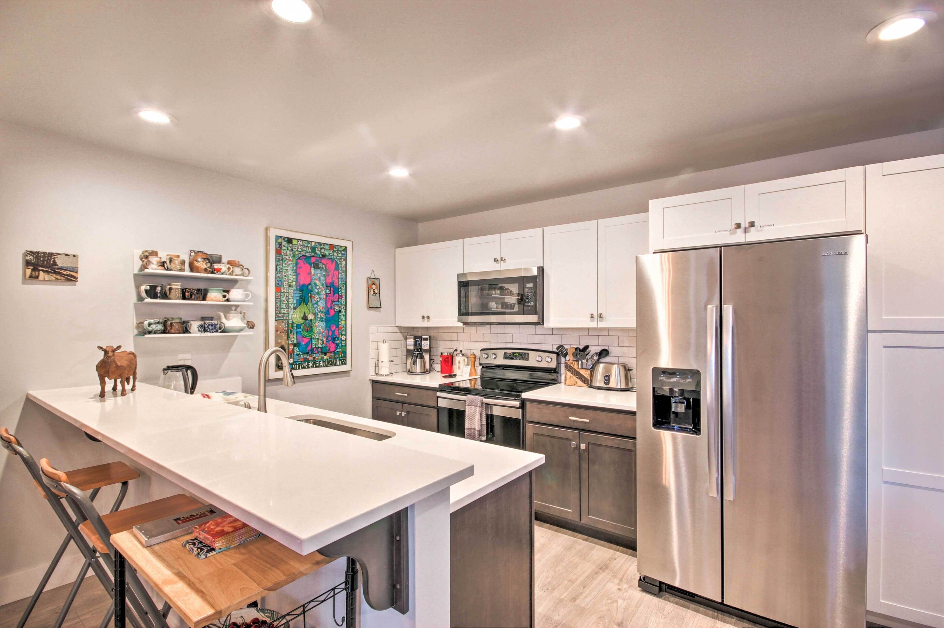 A modern kitchen with white cabinets, stainless steel appliances, and a central island.