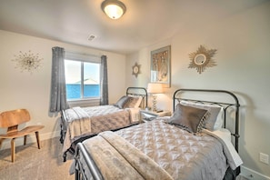 A bedroom with two beds, a wooden chair, a window with curtains, and decorative wall art. - Quiet Home by Dtwn Livingston: Hike, Fish & Ski! (Livingston)