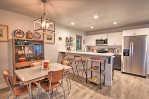 A modern kitchen with a dining area, stainless steel appliances, and a wooden dining table. - Quiet Home by Dtwn Livingston: Hike, Fish & Ski! (Livingston)