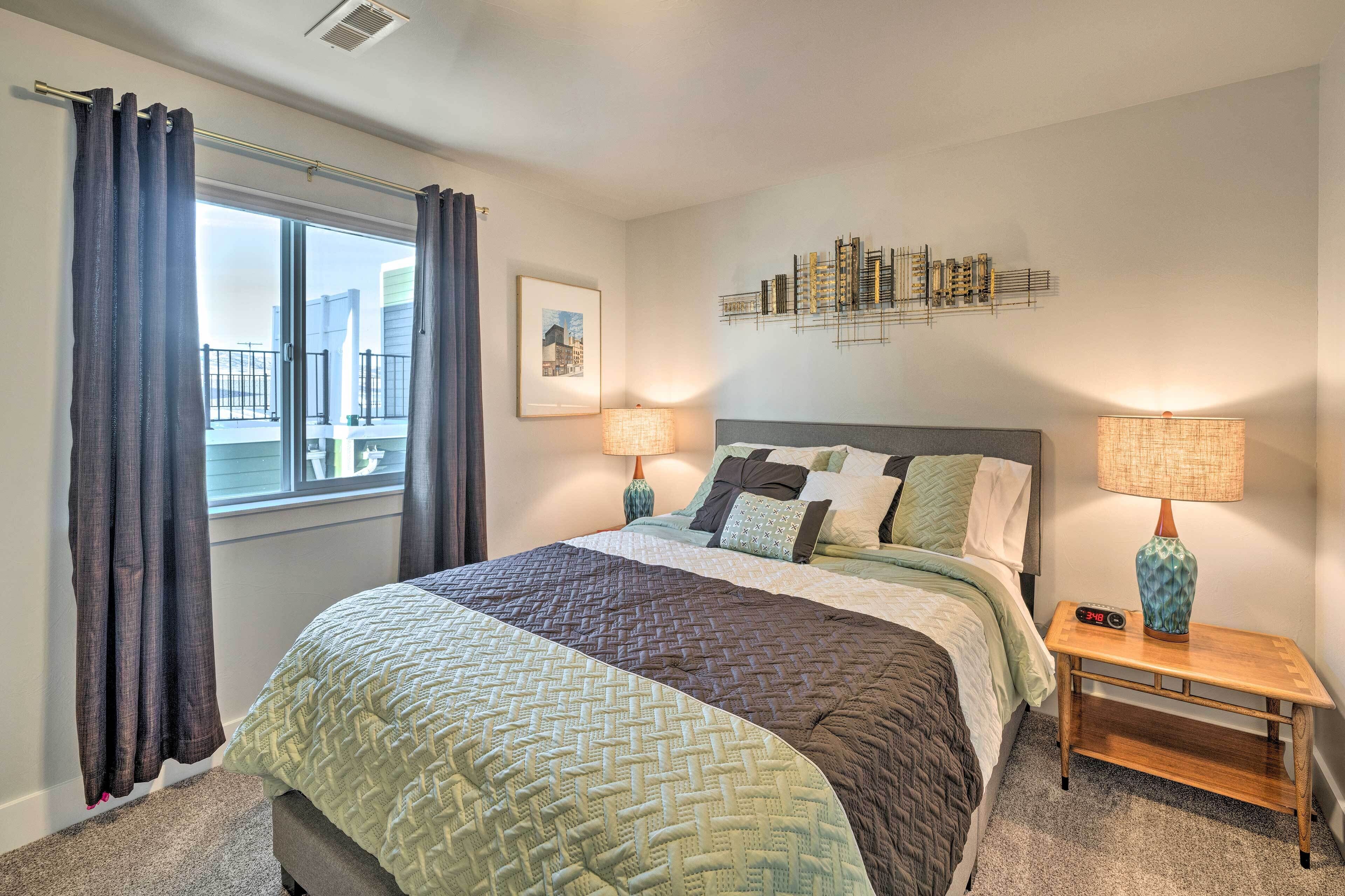 A neatly arranged bedroom with a large bed, two bedside lamps, a wall art piece, and a window with curtains.