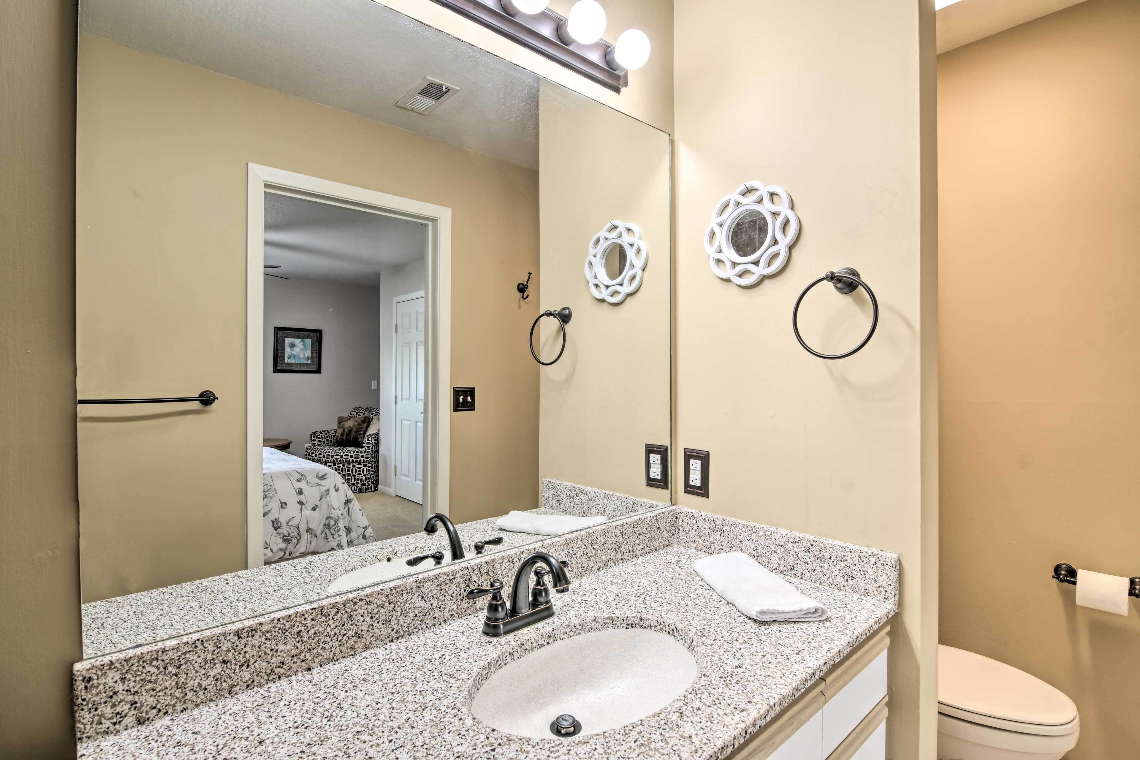 A bathroom with a granite countertop sink, a large mirror, and a toilet.