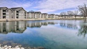 A row of multi-story residential buildings with balconies, a calm body of water in front, and a clear sky. - Holiday Hills Resort Condo w/ Hot Tub Access (Branson)