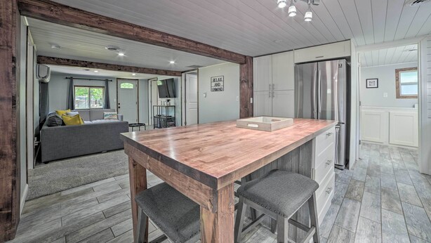 A spacious kitchen with a wooden island, stainless steel appliances, and a view into the living area.