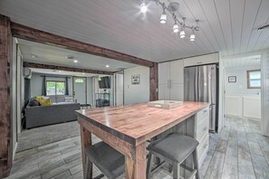 A spacious kitchen with a wooden island, stainless steel appliances, and a view into the living area. - Prudenville Retreat w/ Yard ~ 1 Mi to Lake! (Prudenville)