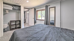 A bedroom with a bed, a wardrobe, a mirror, and a window.