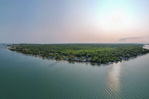 Une vue aérienne d’une petite île, couverte d’une végétation luxuriante et parsemée de quelques bâtiments, entourée d’une eau calme.