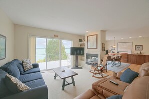 A living room with a sofa, a coffee table, a TV, and a fireplace. - Lakefront De Tour Village Home w/ Deck & Fire Pit! (De Tour Village)