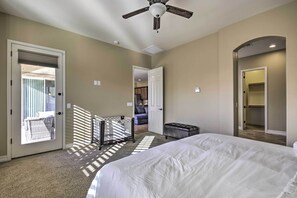 A bedroom with a large bed, a ceiling fan, a walk-in closet, and a view of the outside balcony. - Updated Goodyear Escape: Remote-work Friendly (Goodyear)
