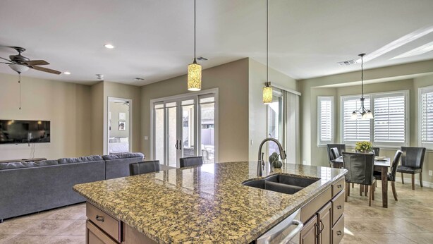 A modern kitchen with granite countertops, a built-in sink, and a dining area with a table and chairs. - Updated Goodyear Escape: Remote-work Friendly (Goodyear)