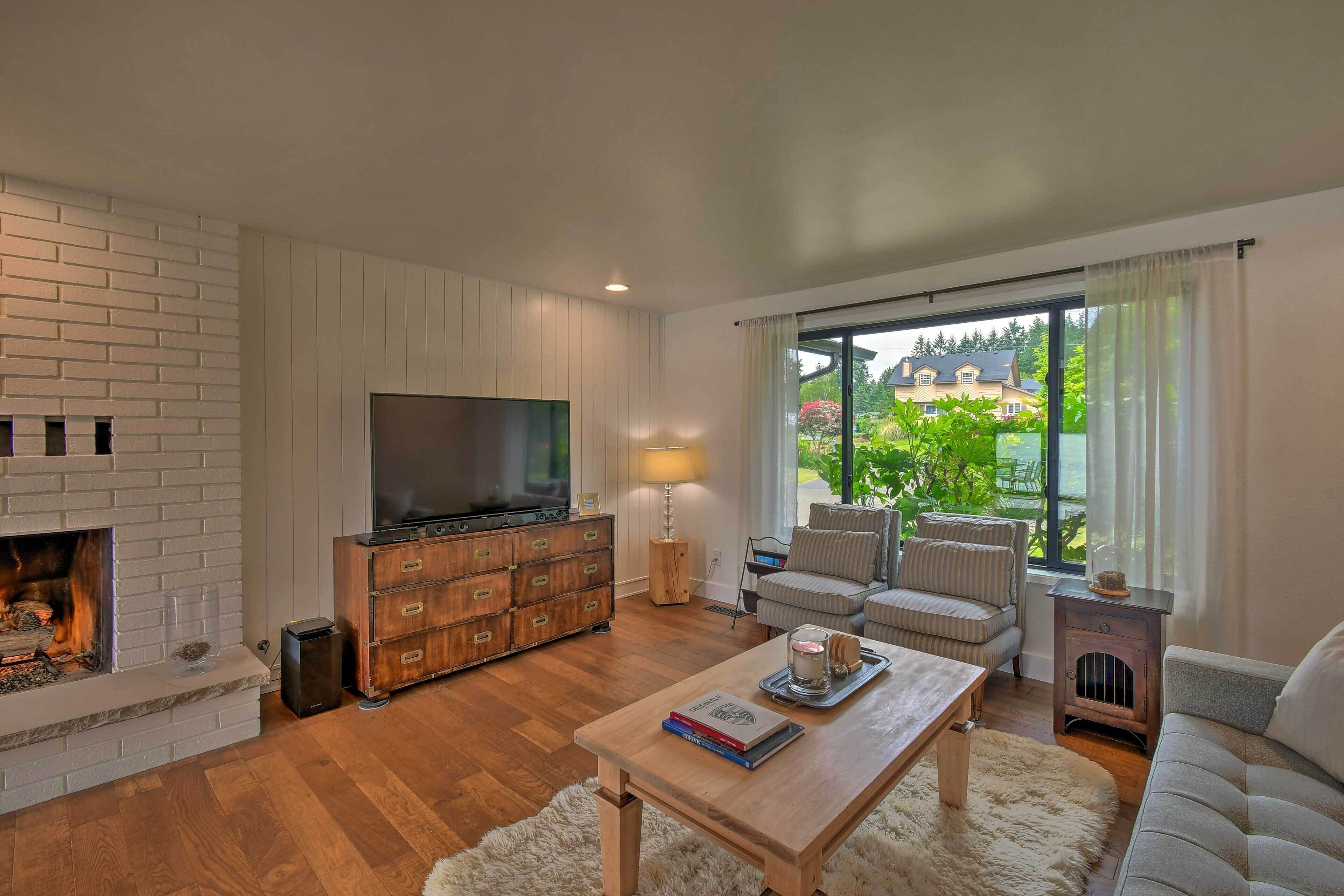 Un salón con chimenea, televisor, sofá y vistas al exterior.