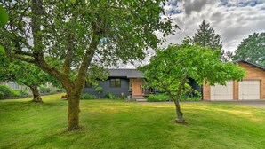Una casa moderna con césped cuidado, un garaje y un árbol grande al frente.