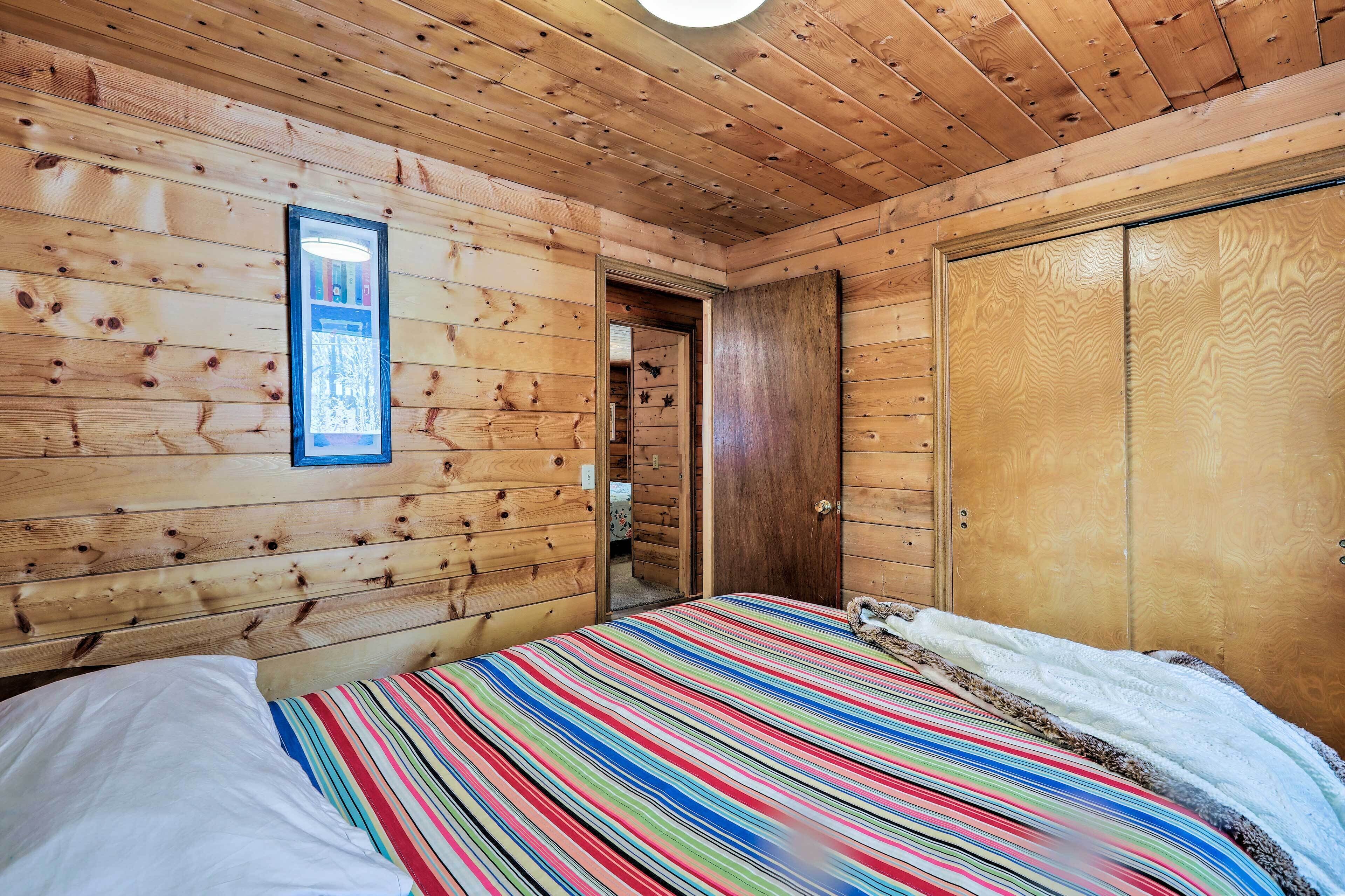 Una habitación de cabaña de madera con una cama, un armario y un cuadro en la pared.