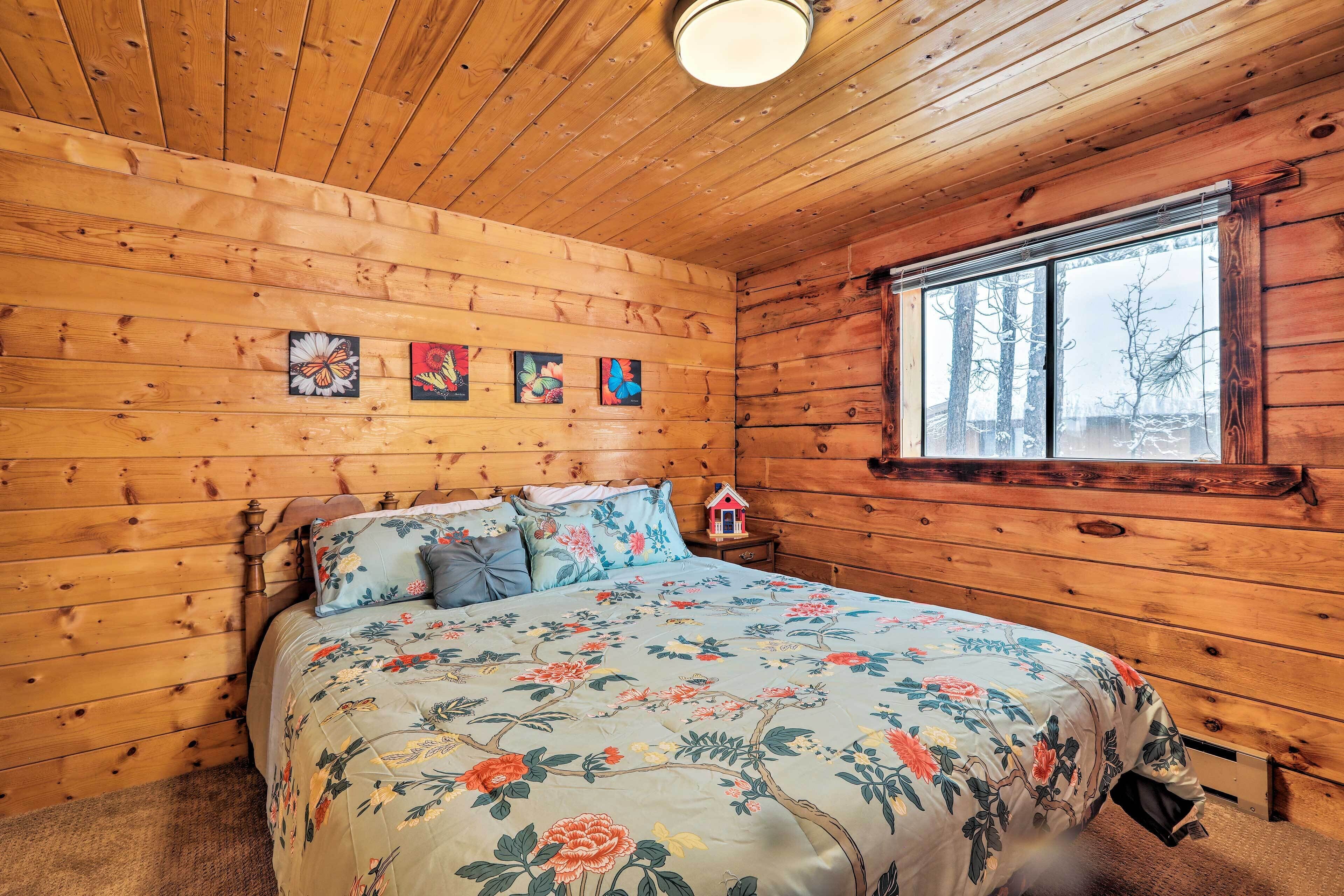 A wooden cabin bedroom with a bed, a nightstand, and a window.