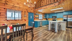A wooden cabin interior with a dining area, kitchen, and a large island with stools. - Furnished Deck: Cabin in Coconino National Forest (Munds Park)
