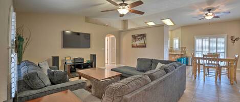 A spacious living room with a large gray sectional sofa, a wooden coffee table, and a ceiling fan.