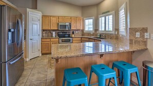 A kitchen with wooden cabinets, a stainless steel refrigerator, a microwave, and a granite countertop. - Temp-controlled Pool: Lake Havasu Escape, Mtn View (Lake Havasu City)