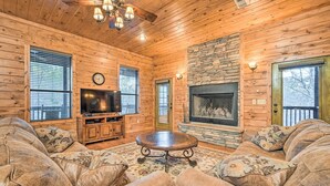 A cozy log cabin interior with a fireplace, wooden walls, a television, and a comfortable seating area. - Broken Bow Cabin w/ Deck, Hot Tub & Fire Pit! (Broken Bow)