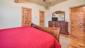 A bedroom with a wooden bed, a dresser, a television, and a ceiling fan. - Broken Bow Cabin w/ Deck, Hot Tub & Fire Pit! (Broken Bow)