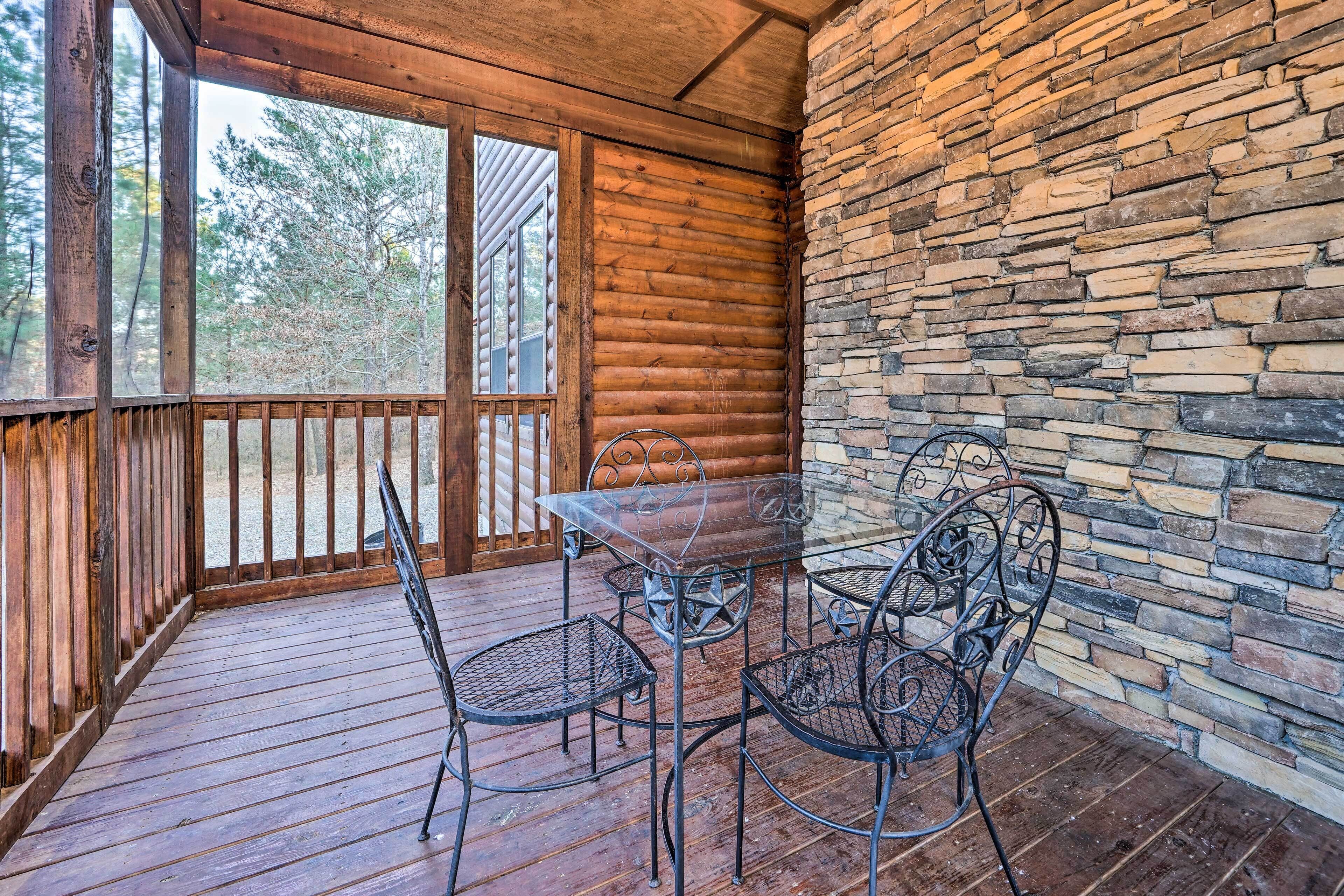 A wooden deck with a glass table and metal chairs, surrounded by stone walls and wooden railings.